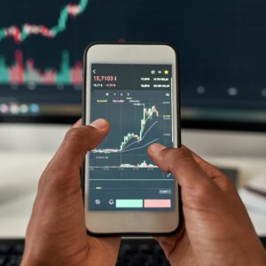 Hands holding smartphone showing trading chart